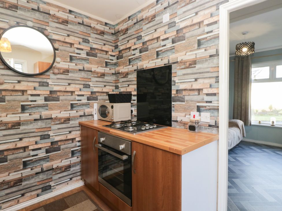 A kitchen with a gas stove and microwave at Beechtree Lodge 56 Denny