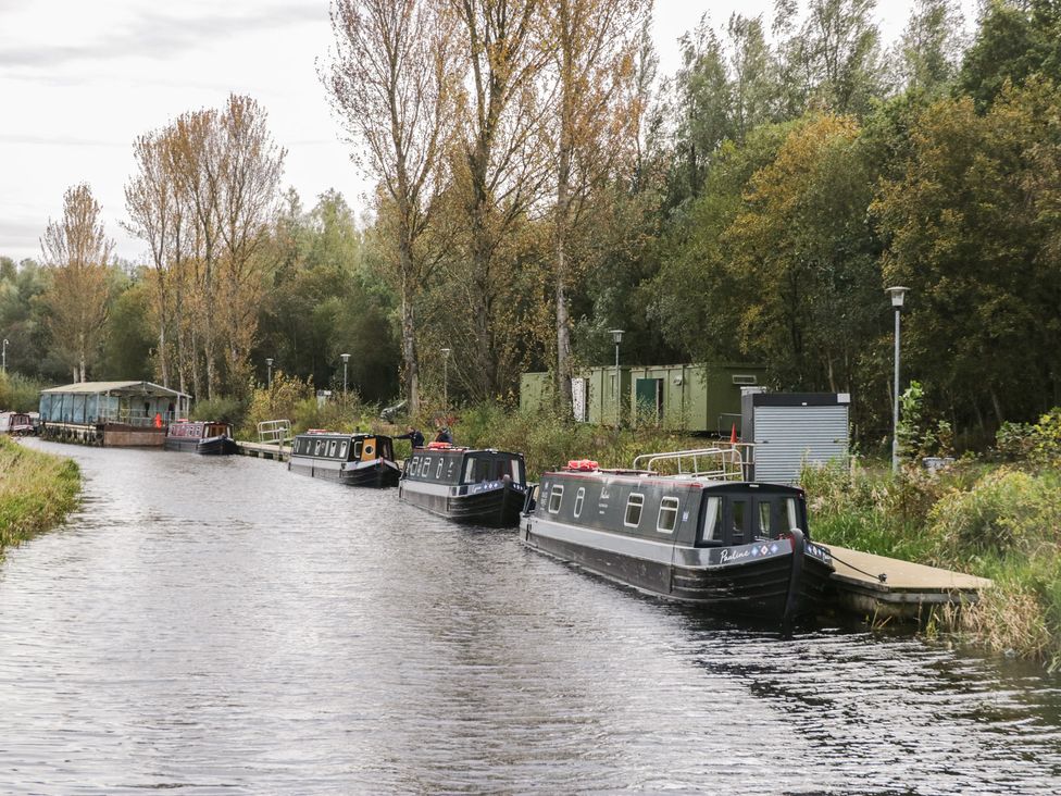 Boats lined along a canal with trees nearby at Beechtree Lodge 56 in Denny