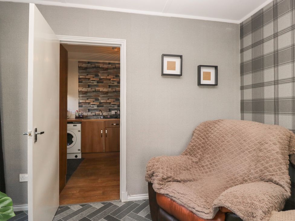 A living room with a sofa and open door to kitchen at Beechtree Lodge 57 Denny