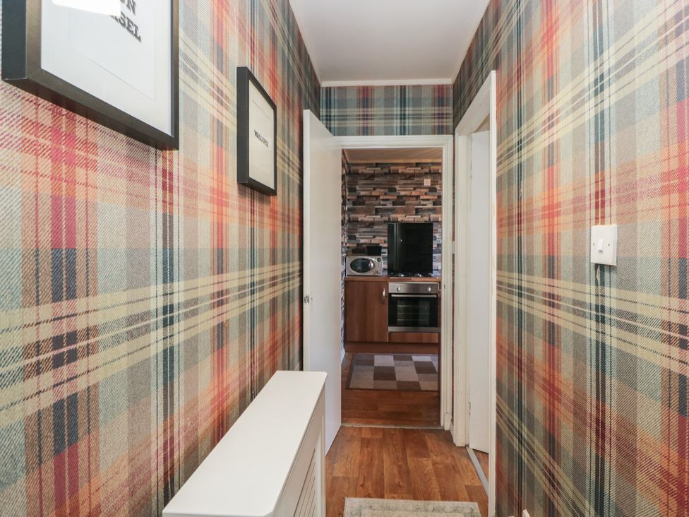 A hallway with patterned wallpaper and an entrance to a kitchen at Beechtree Lodge 57 Denny