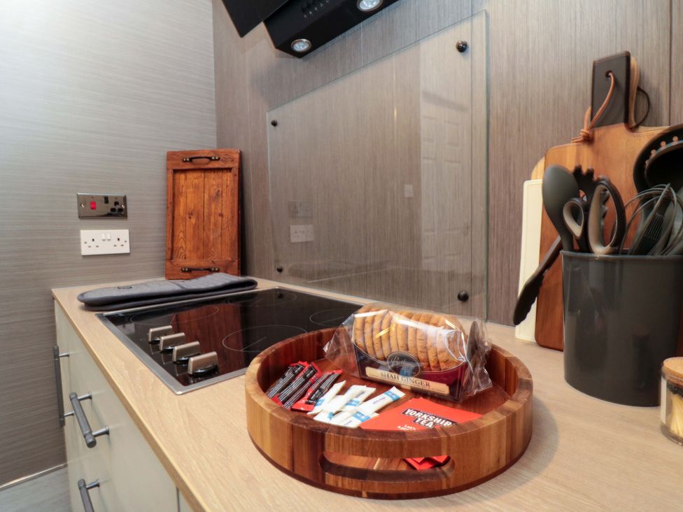 A kitchen with a cooktop and utensils on a wooden tray at Isla’s Sea Forge Saltburn-by-the-Sea