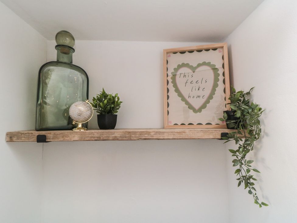 A shelf with a glass bottle, globe, plants, and art print at Isla’s Sea Forge in Skinningrove