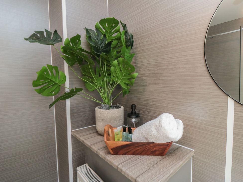 A bathroom with a towel and bath products on a shelf at Isla’s Sea Forge in Skinningrove