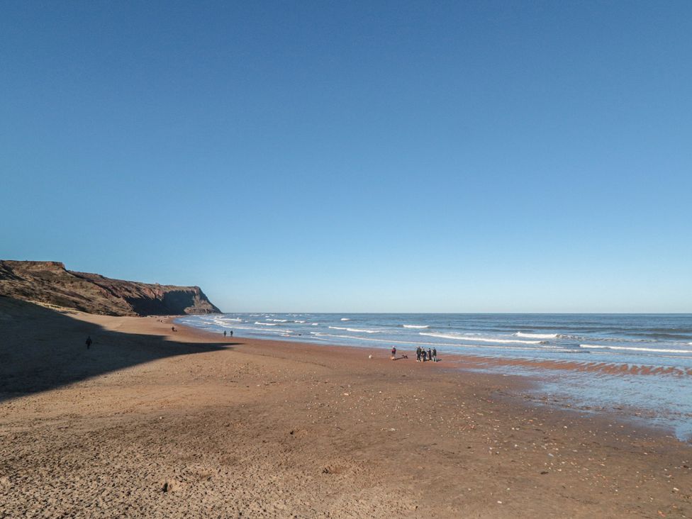 A beach with people walking along the shore at Isla’s Sea Forge in Skinningrove