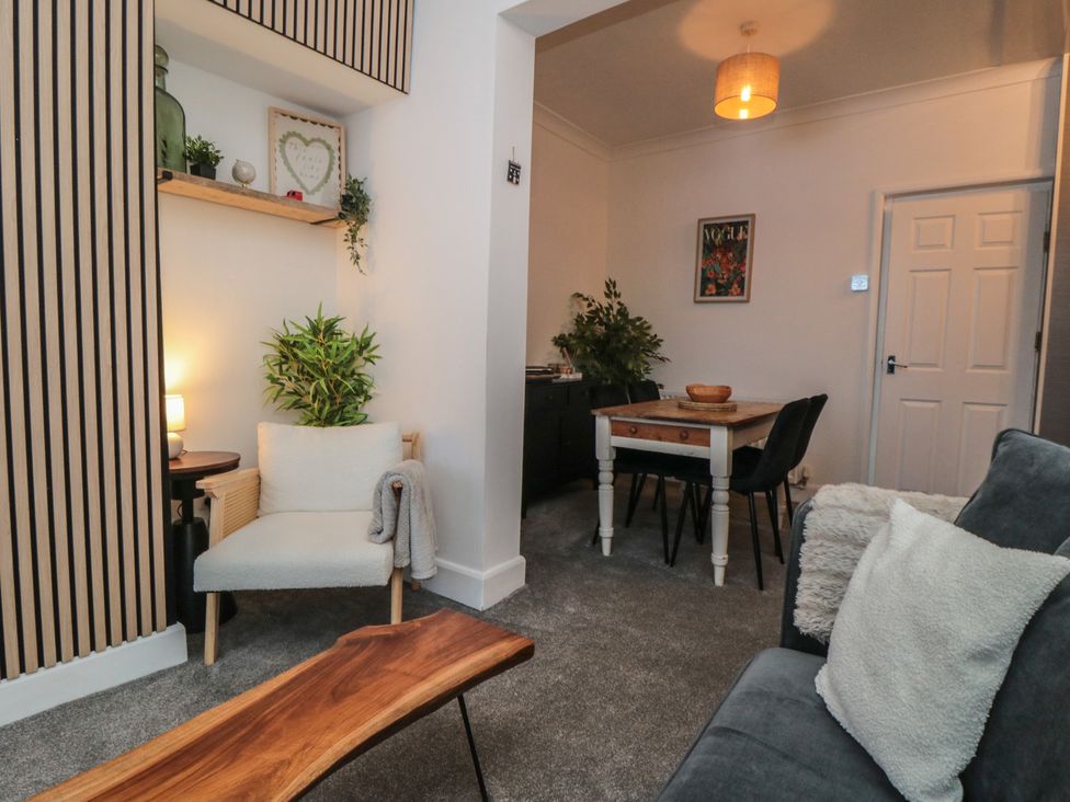 A living room with a chair, table, and plants at Isla’s Sea Forge in Skinningrove