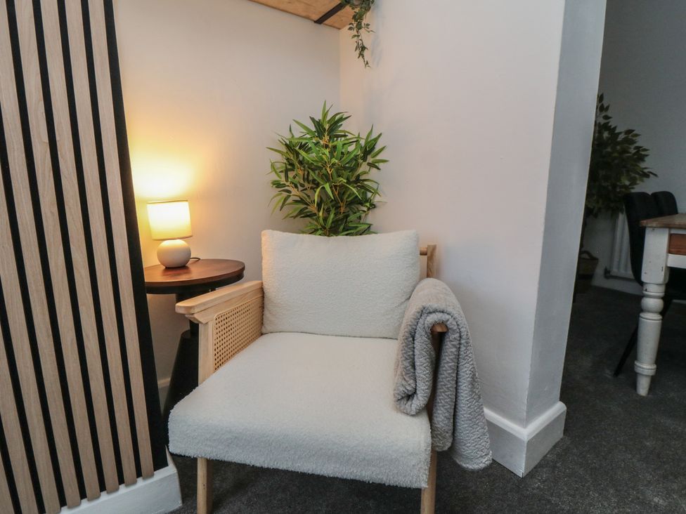A chair with a plant and lamp in a living room at Isla’s Sea Forge in Skinningrove