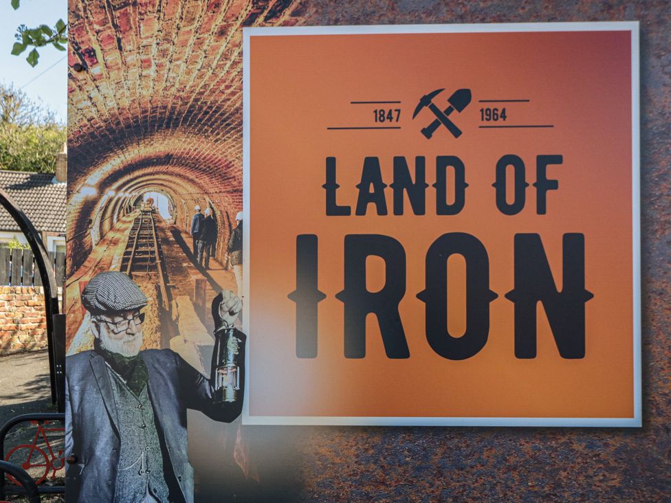 A sign displaying 'Land of Iron' with a historical image at Isla’s Sea Forge Skinningrove