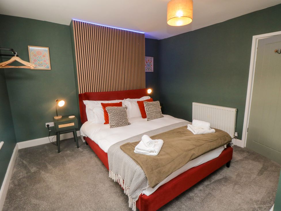 A bedroom with a double bed, nightstand and wall decor at Isla’s Sea Forge in Skinningrove