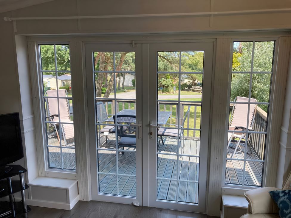 A living room with patio doors viewing a deck at Caravan 38 in Newport