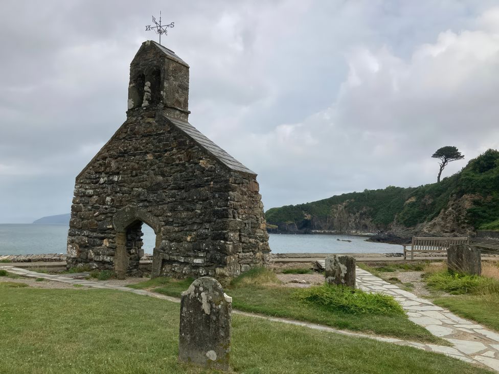 A stone church near water with a pathway and bench at Caravan 38 Newport