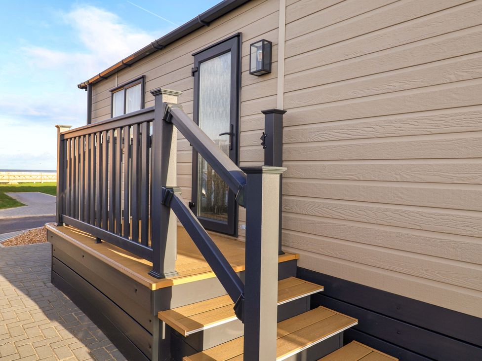 Steps leading to a door with a railing at Paws By The Sea in Norwich