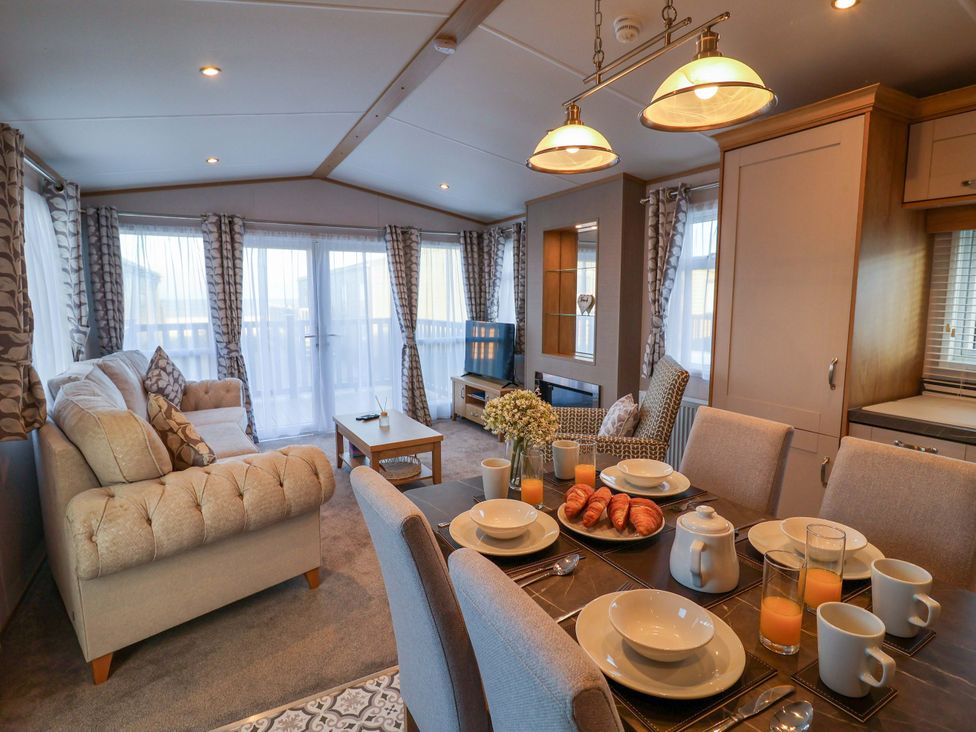 A living room with a dining table and sofa at Paws By The Sea in Norwich