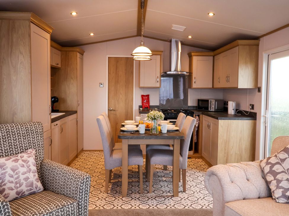 A kitchen with dining table and chairs at Paws By The Sea in Norwich