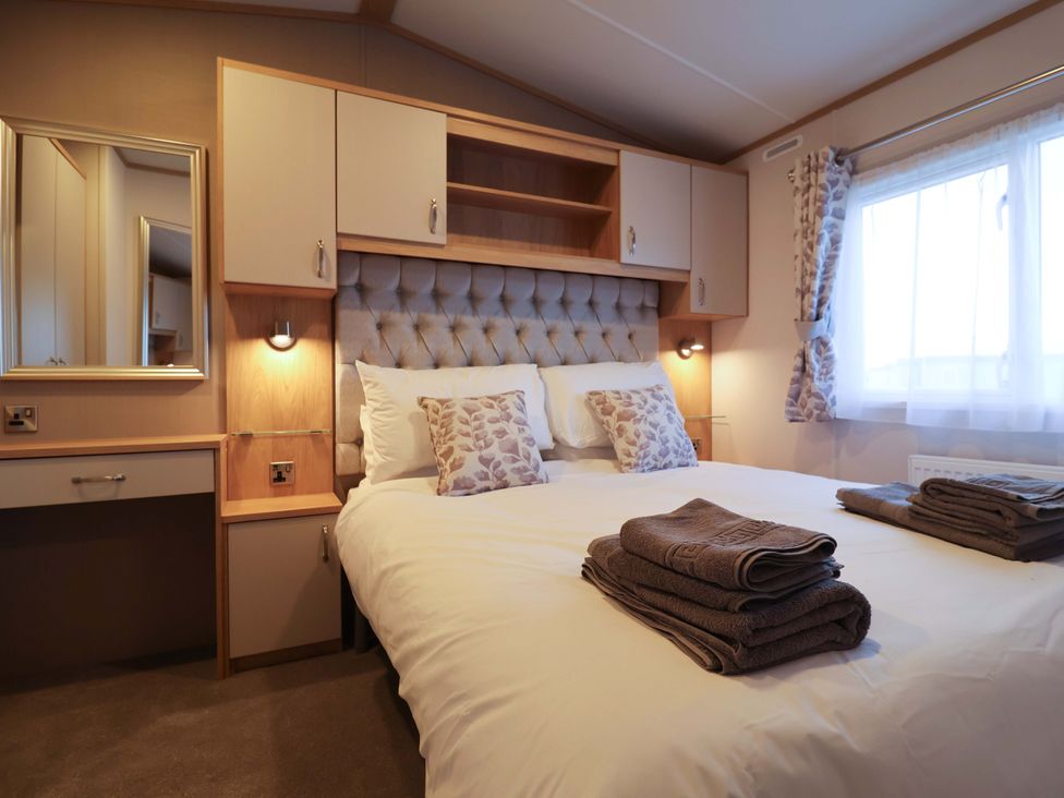 A bedroom with a bed and bedside lamp at Paws By The Sea in Norwich