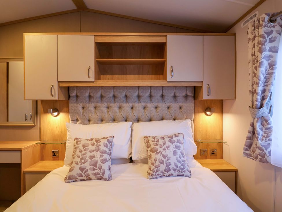 A bedroom with a bed and wall cabinets at Paws By The Sea in Norwich