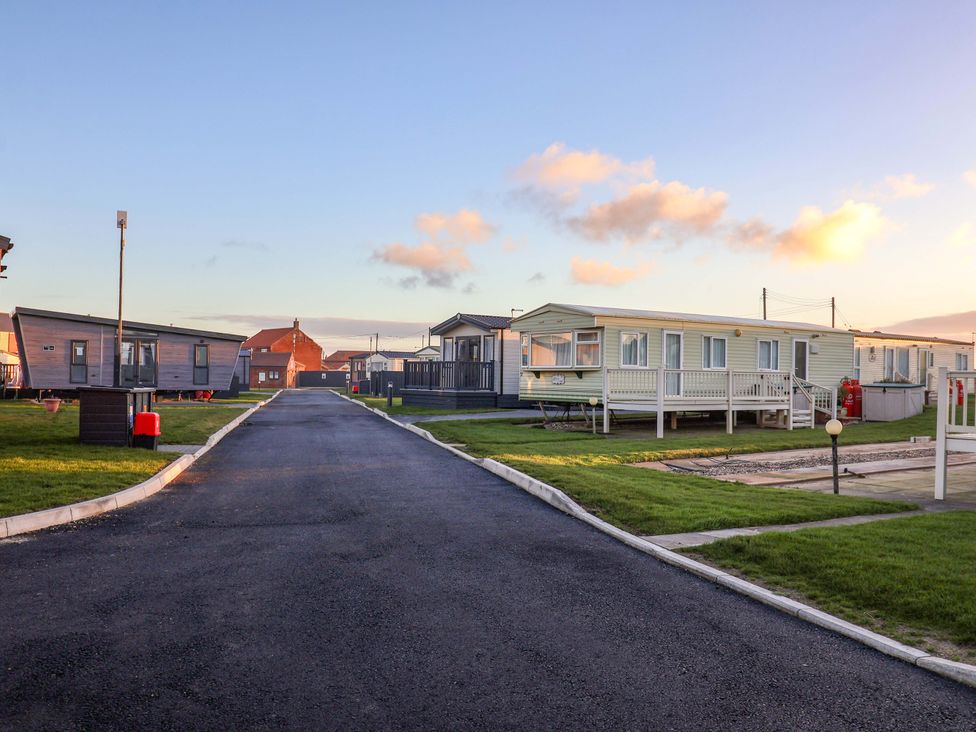 An outdoor area with caravans and a path at Paws By The Sea in Norwich