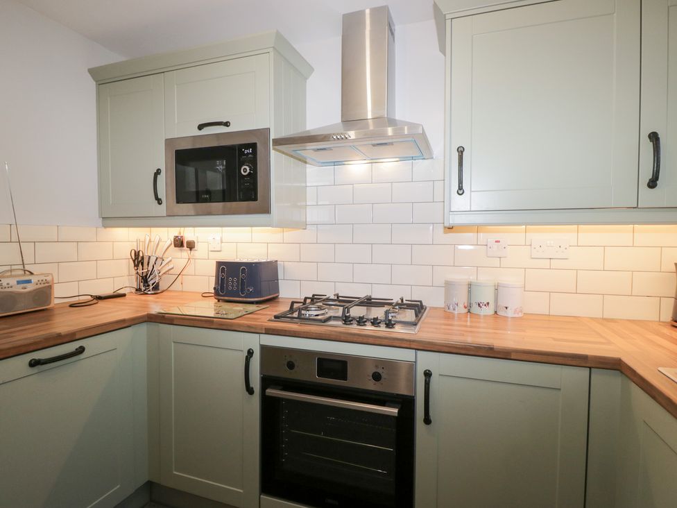 A kitchen with cabinets, microwave, cooker, and toaster at Mables in Wigton