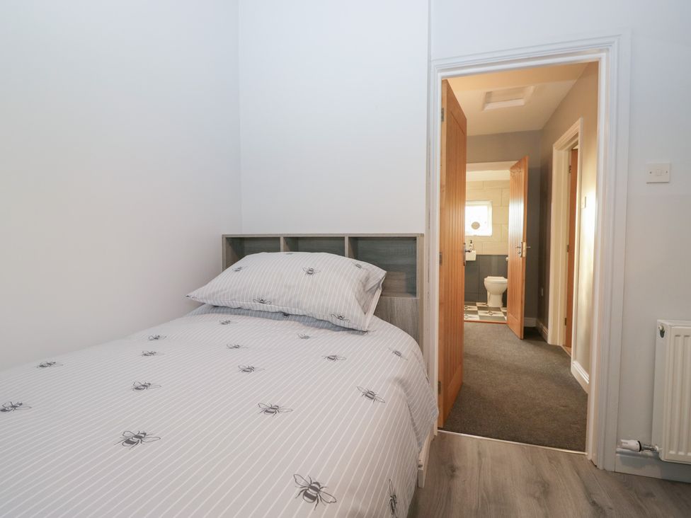 A bedroom with a bed and doors leading to bathroom at Mables in Wigton