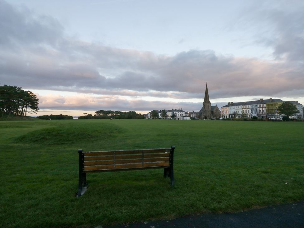 A bench overlooking grass and a church at Mables in Wigton