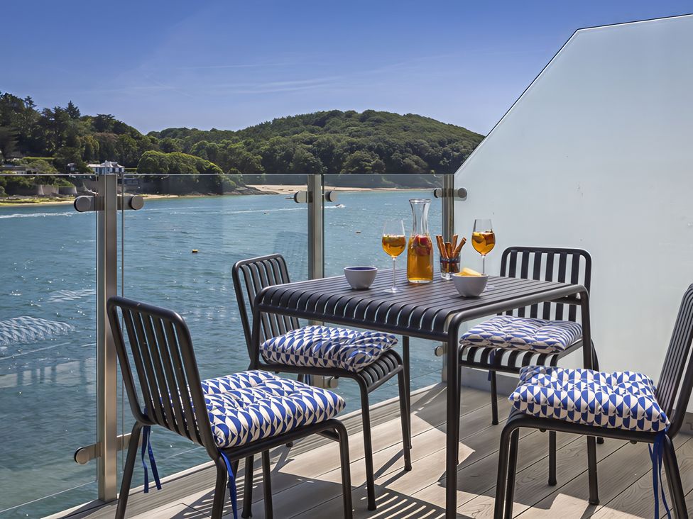 An outdoor seating area with a table and chairs overlooking the water at Villa 8, Estura Salcombe