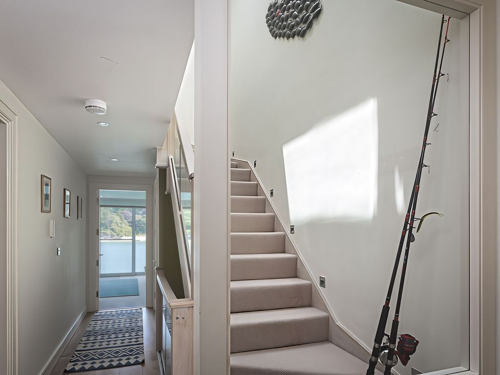 A hallway with a staircase and fishing rod at Villa 8, Estura Salcombe