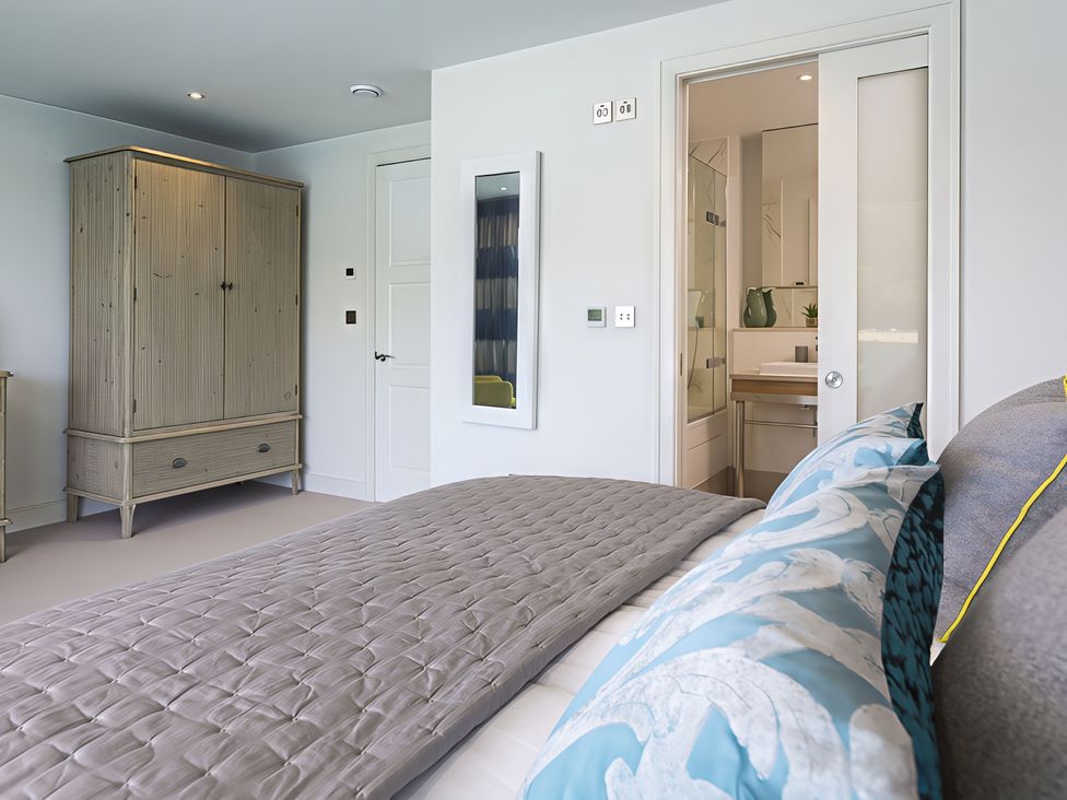 A bedroom with a bed and wardrobe at Villa 8, Estura in Salcombe