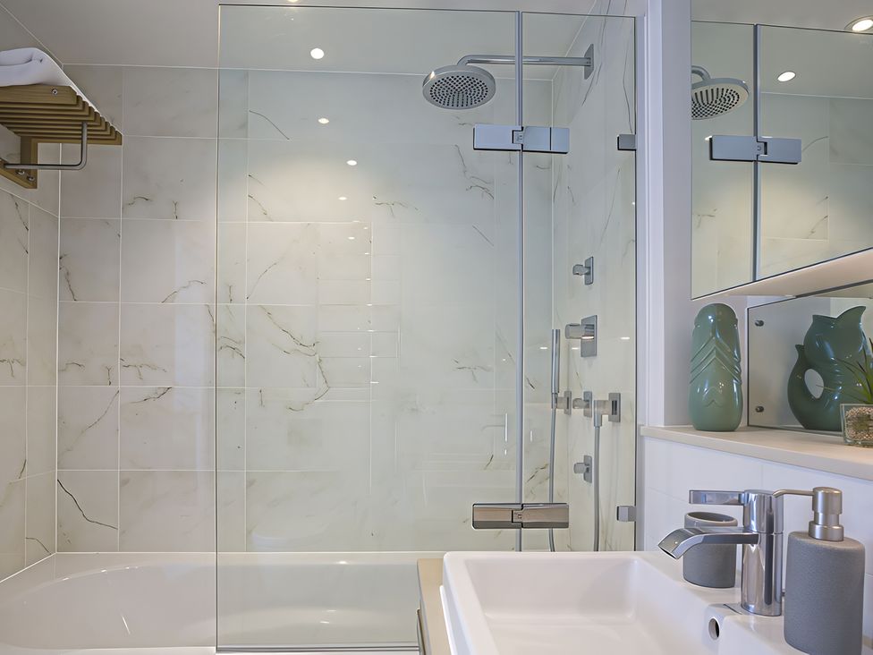 A bathroom featuring a shower, bathtub, sink, and green decorative vase at Villa 8, Estura in Salcombe