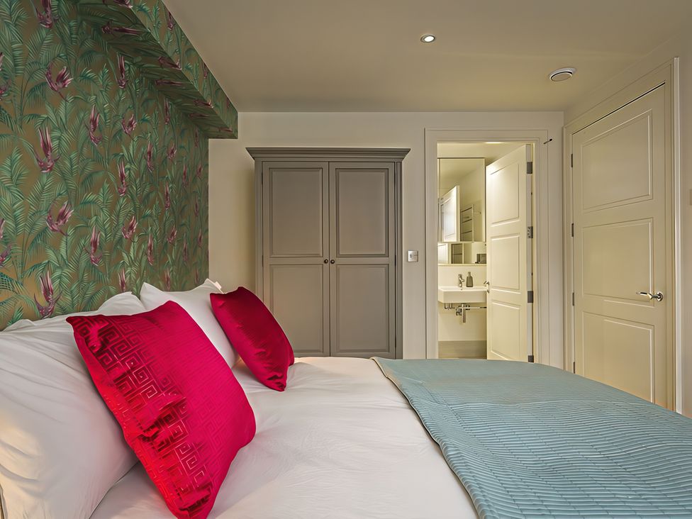 A bedroom with a bed and wardrobe at Villa 8, Estura in Salcombe