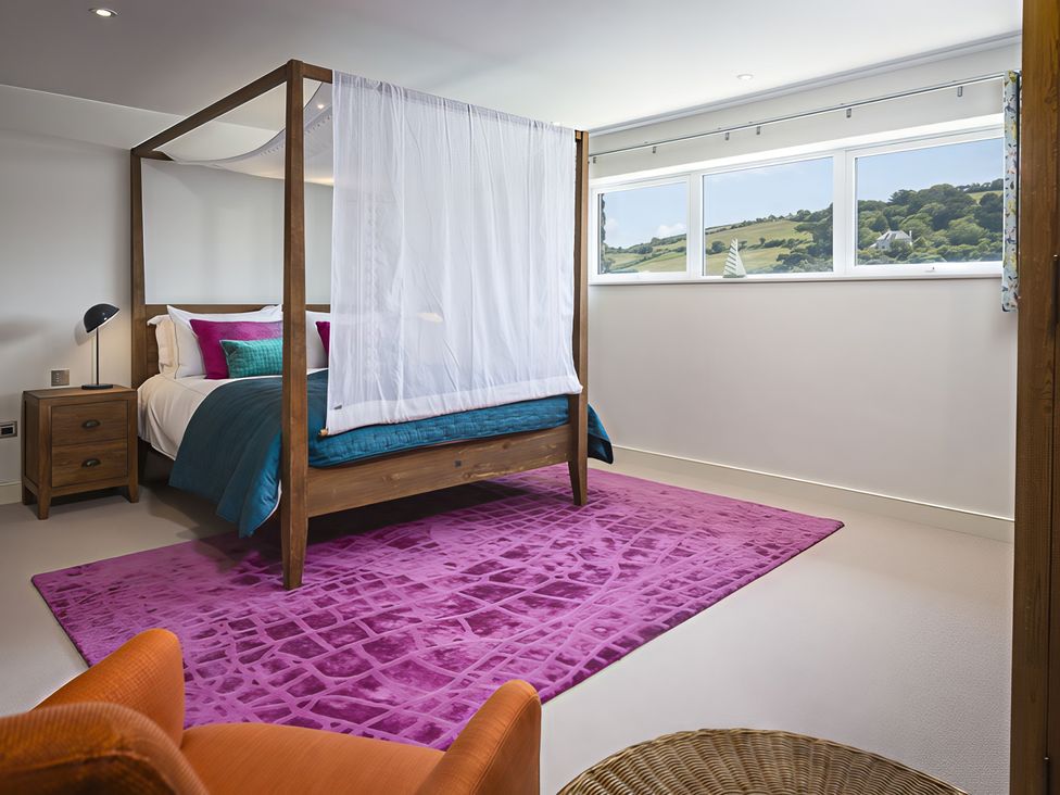 A bedroom with a four-poster bed and windows at Villa 8, Estura in Salcombe