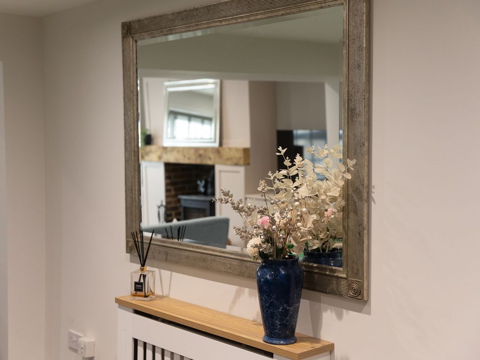 A mirror and vase with flowers on a table in a living room at 6 Front Street