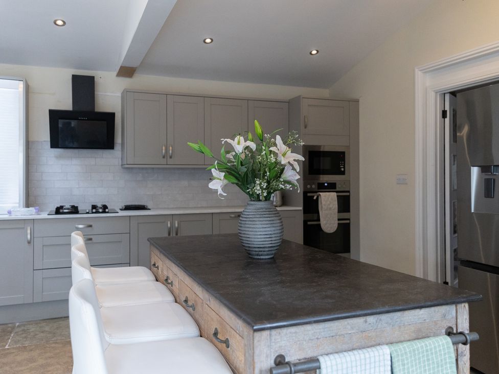 A kitchen with a table, chairs, stove, and a vase of flowers at 6 Front Street
