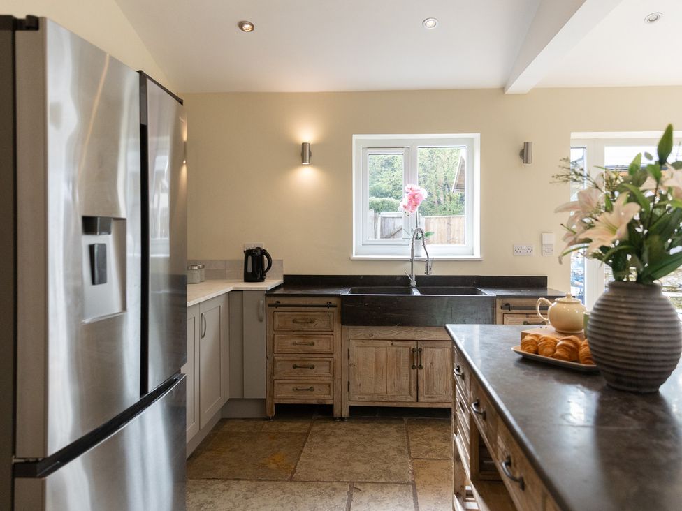 A kitchen with a sink, refrigerator, and flowers on the countertop at 6 Front Street