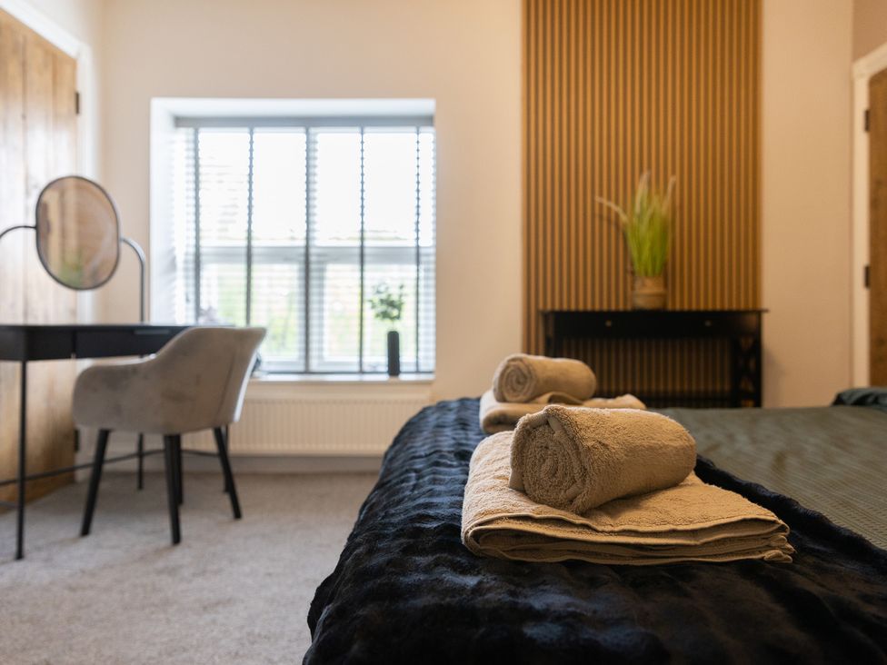 A bedroom with towels on a bed and a desk with a mirror at 6 Front Street 