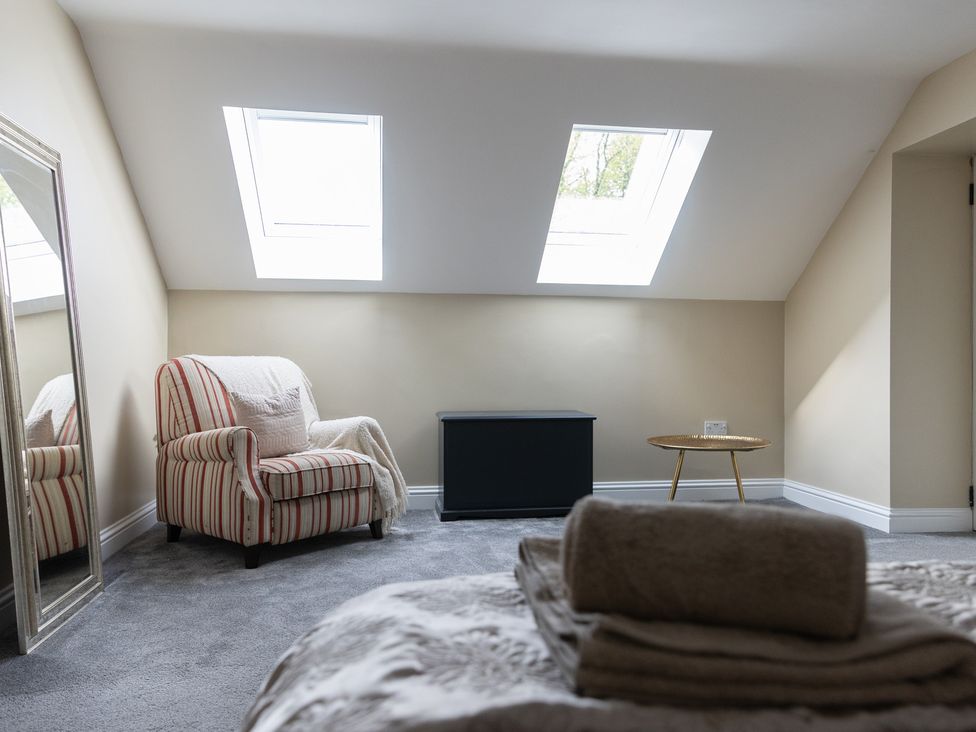 A bedroom with a striped armchair and a mirror at 6 Front Street