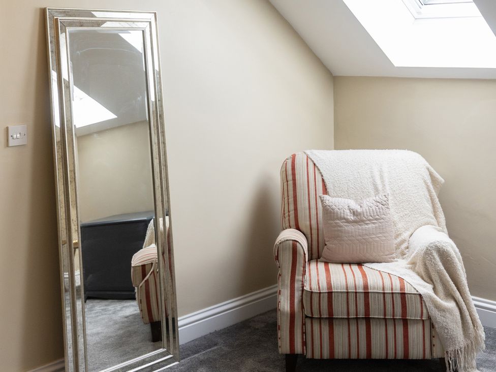 A living room with a striped chair and a mirror at 6 Front Street 