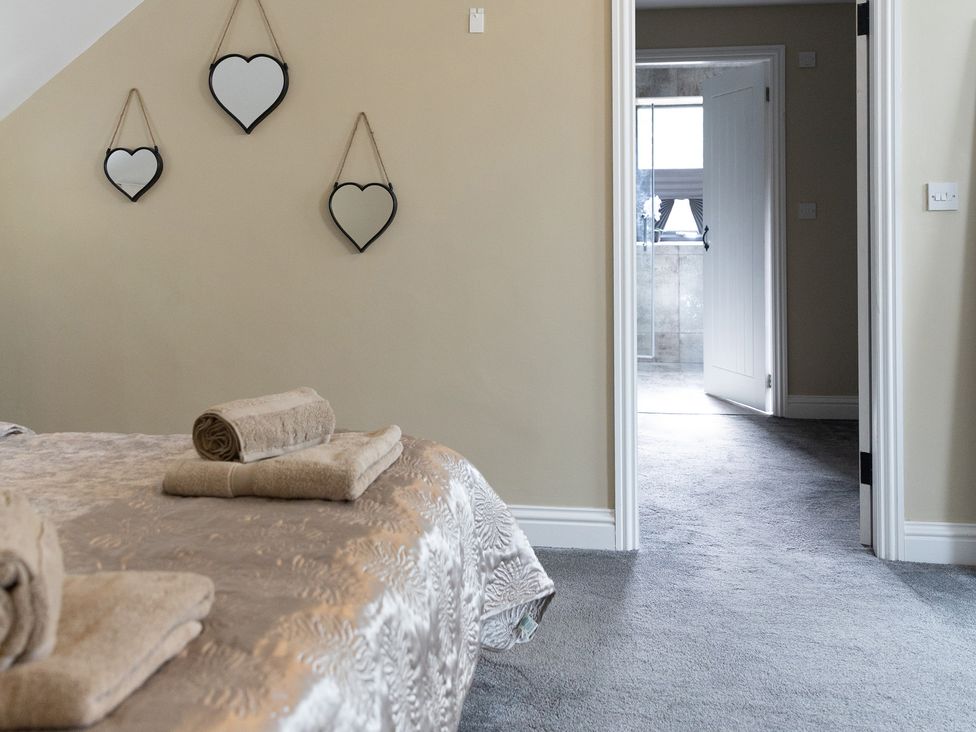 A bedroom with towels on the bed and a doorway leading to another room at 6 Front Street