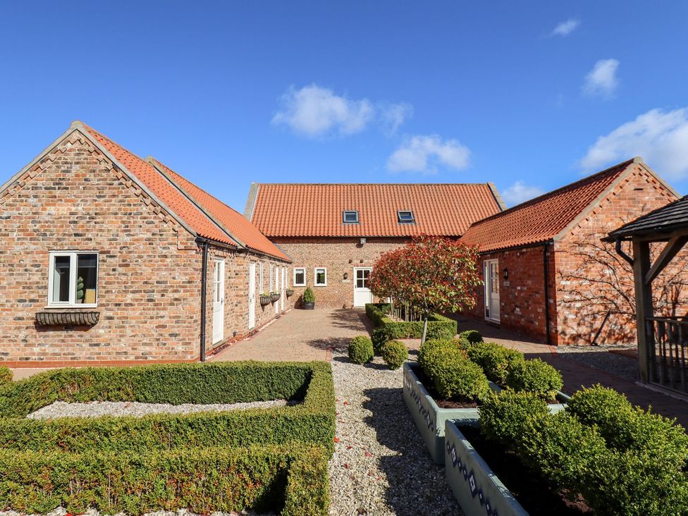 An outdoor view of a courtyard with buildings and garden at The Stables in Louth