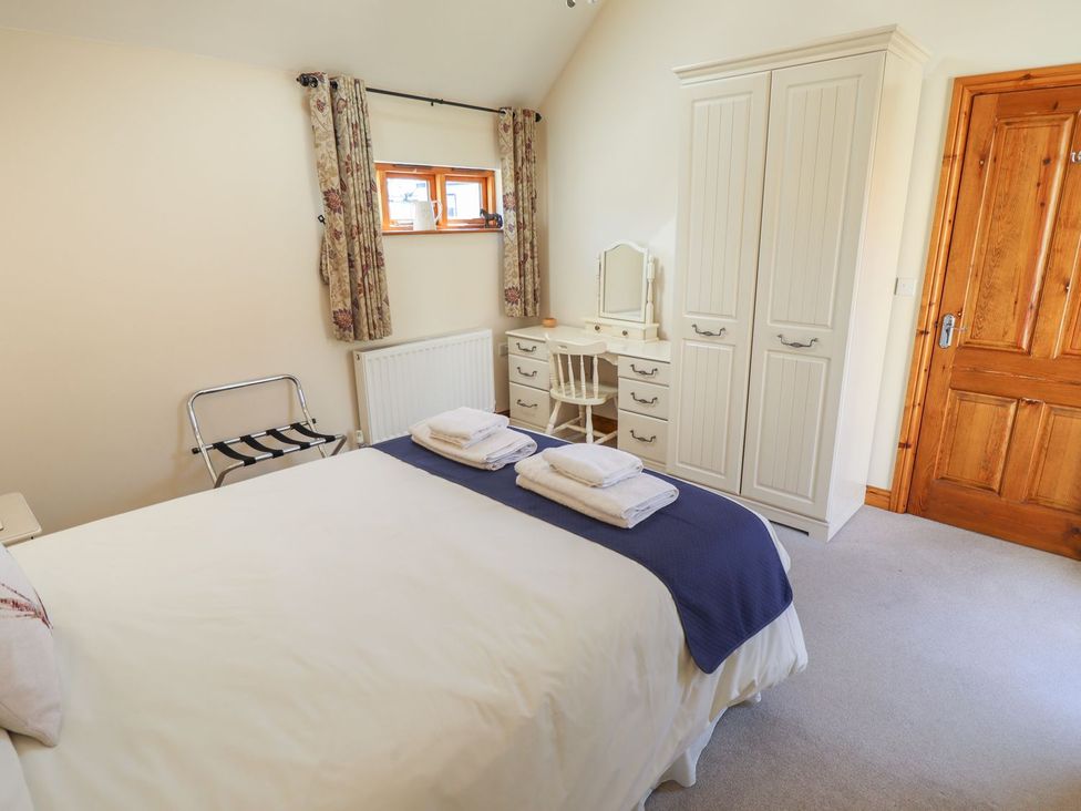 A bedroom with a bed and wardrobe at The Stables in Louth