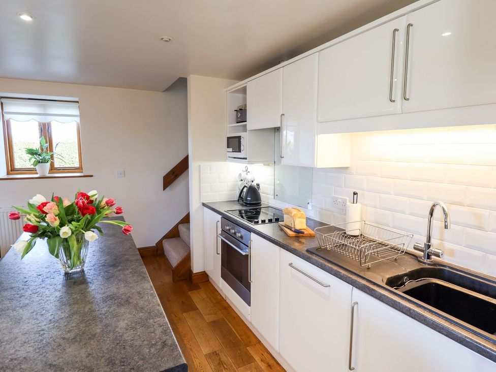 A kitchen with a sink, stove, and flowers at The Mill House in Louth