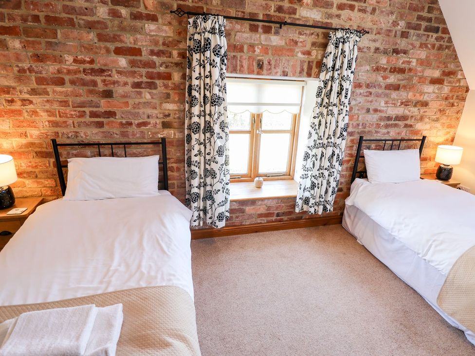 A bedroom with two single beds and a window at The Mill House in Louth
