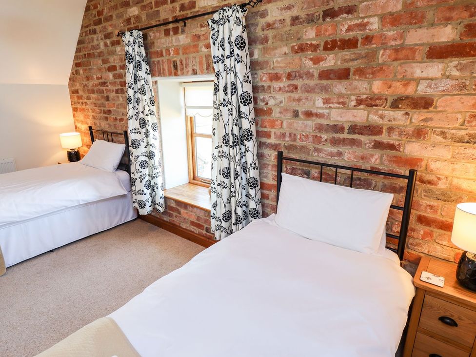 A bedroom with two beds and a window at The Mill House in Louth