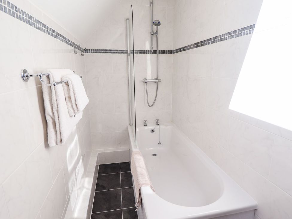 A bathroom with a bathtub and towels at The Mill House in Louth
