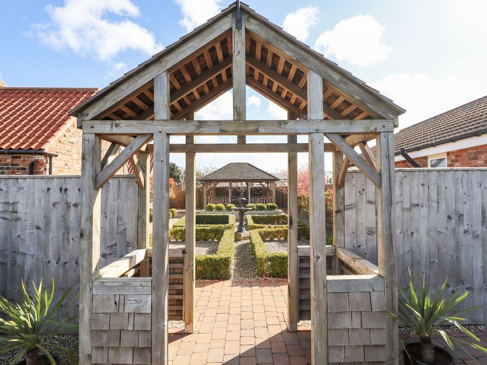 A garden featuring a wooden archway and path at The Mill House in Louth