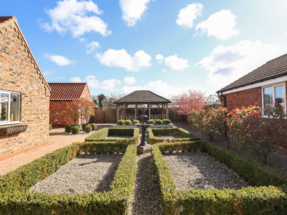 A garden with hedges and a fountain at The Mill House in Louth