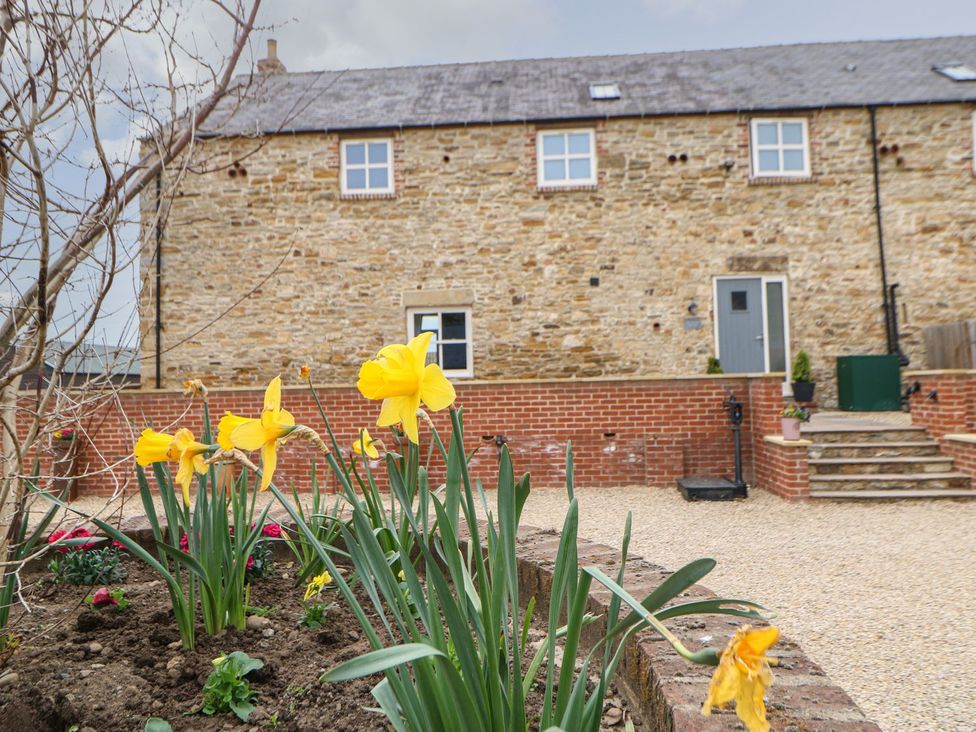 An outdoor area with flowers and a stone building at The Granary in Durham