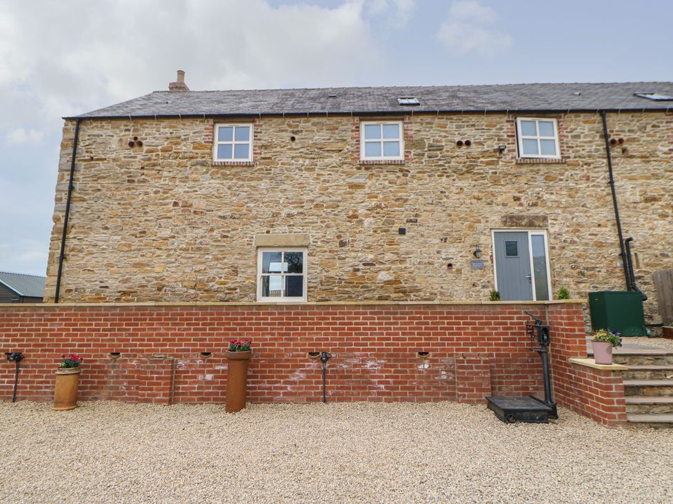 A stone wall building with windows and door in a gravel area at The Granary Durham