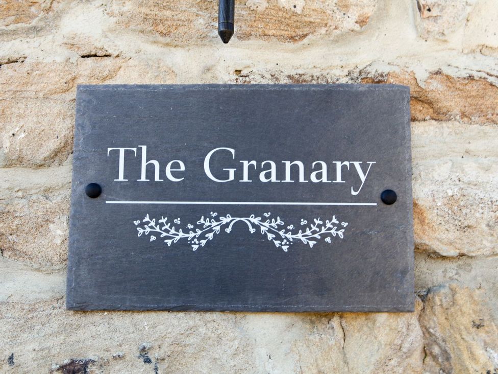 A sign that reads The Granary on a stone wall