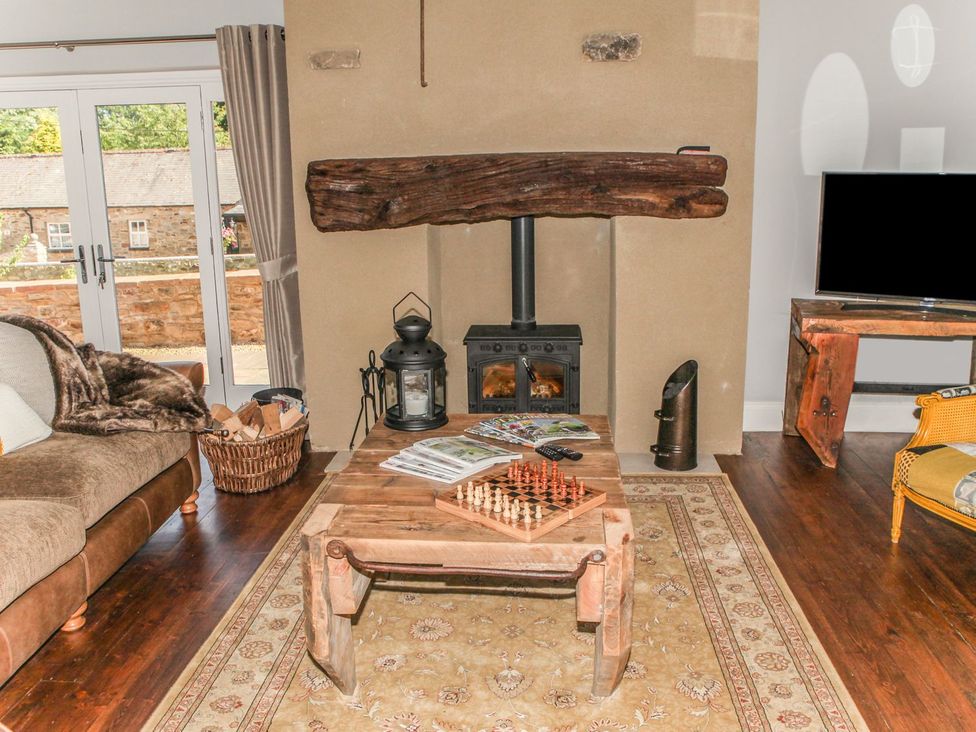 A living room with a sofa, coffee table, fireplace, and television at The Granary in Durham