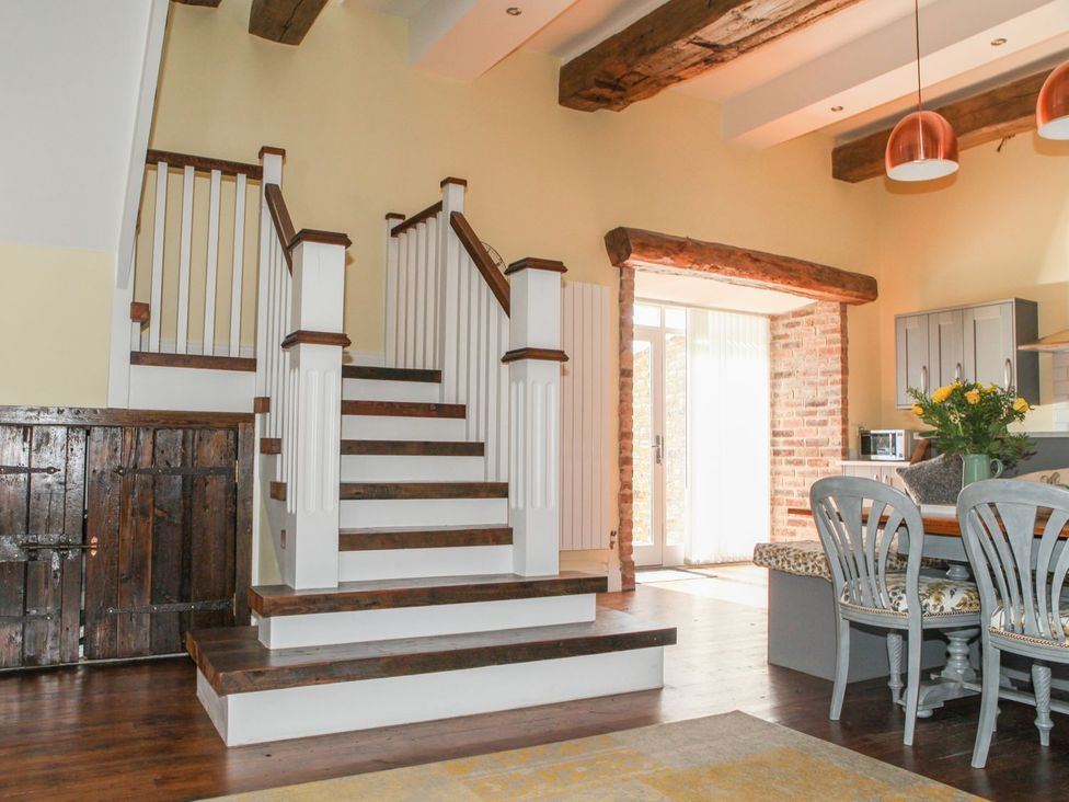 A living room with stairs and a table with chairs at The Granary in Durham
