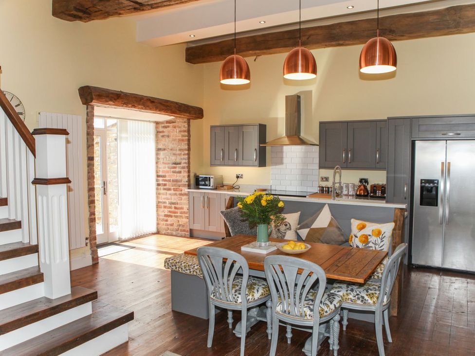 A kitchen with a table and chairs and a refrigerator at The Granary in Durham